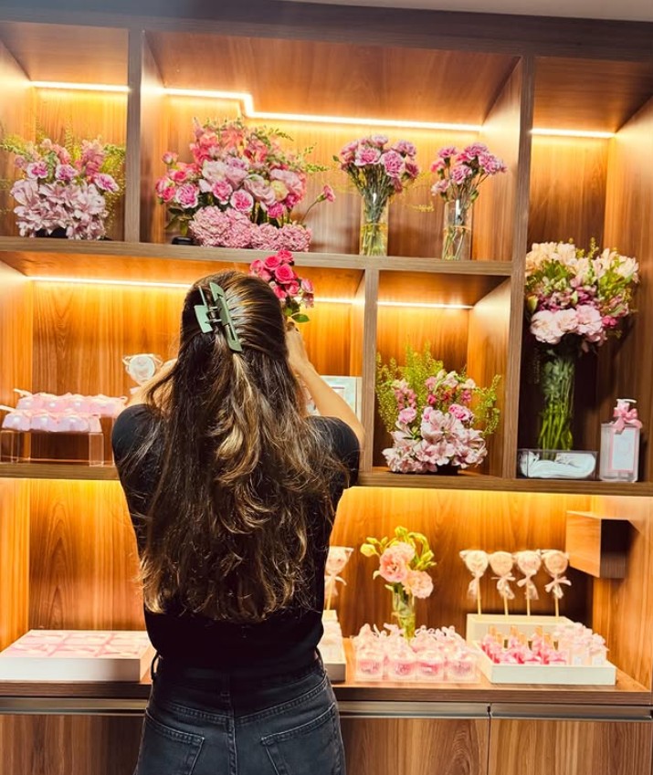 Mívia ajustando flores e ambientação nas prateleiras